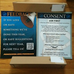 A photo of a consent poster and a feedback poster at Penguicon.