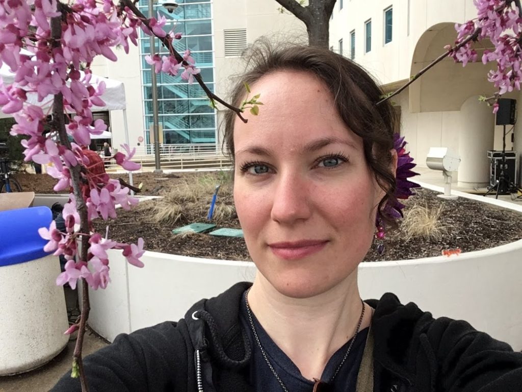 Dark haired woman with tree behind her